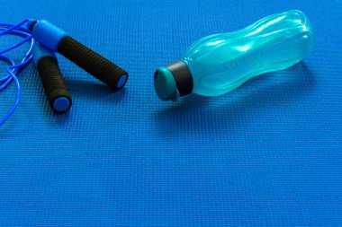 Yoga minderinin üstündeki atlama ipinin yanında şişe ya da su. Eğitim ve dinlenme kavramı. Spor ve Sağlık