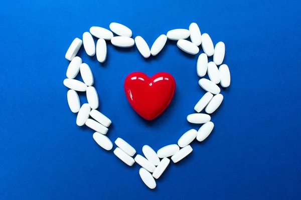 Red heart with pills on blue background