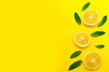 Dilimlenmiş limon ve nane parlak sarı bir arka plan üzerinde yaprakları. Afiş, web sitesi, blogtasarımı için arka plan. Kopyalama alanı