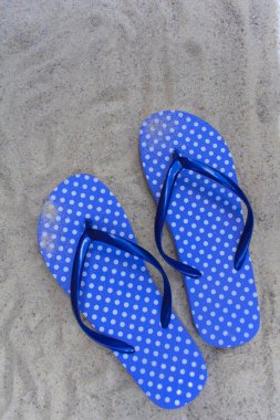 Kumlu bir plajda mavi parmak arası terlik. Yukarıdan görüntüle