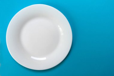 Mavi arka planda beyaz yuvarlak plaka. Yukarıdan bak. Boşluğu kopyala.