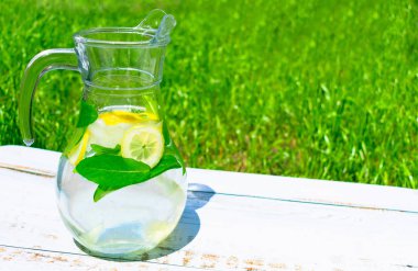 Yeşil çim bir arka plan üzerinde buz ile limonata ve paspaslar ile Sürahi. Alkolsüz içecekler kavramı. Close.. Kopyalama alanı