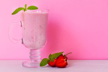 Çilekli milkshake, çilek ve nane pembe bir arka plan üzerinde. Kopyalama alanı