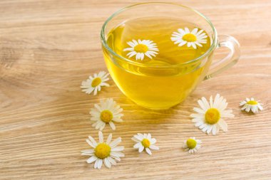 Tahta bir masada bir fincan papatya çayı. Tedavi edici bitkisel çay. Faydalı çay.