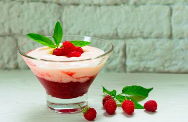 Beyaz bir masada ahududu ve nane ile süslenmiş berry mus ile Yoğurt.