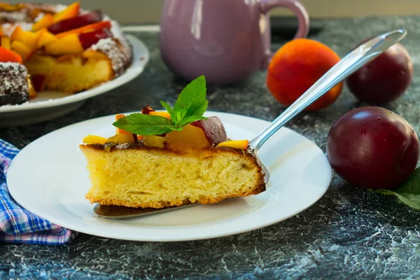 Bir tabak nane bir yaprak ile süslü şeftali ve erik ile pasta bir parça. Bir dissert hazırlama.
