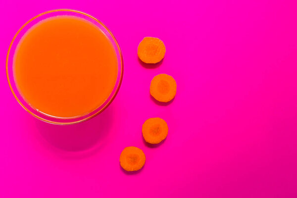 Carrot juice is isolated on a pink background. View from the top. Copy space.