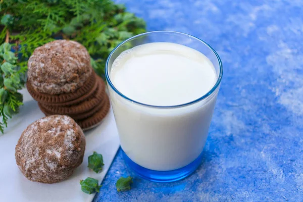 Glass of milk with cookies on the table. On a light blue background.