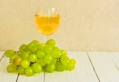 Beyaz ahşap arka planda bir kadeh beyaz şarap ve üzüm. Kopyalama alanı.