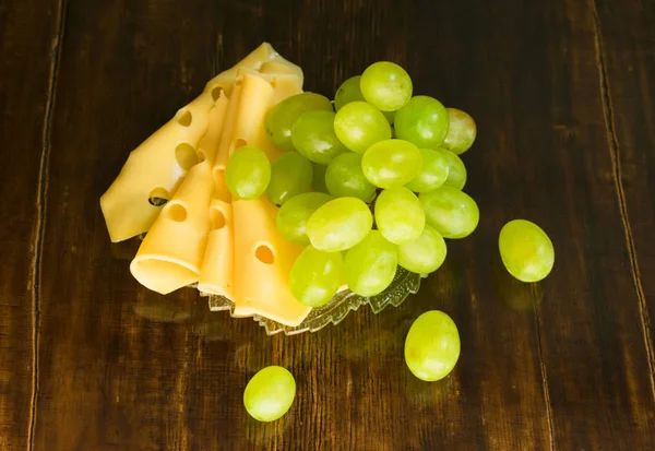  Ahşap bir arka plan üzerinde üzüm ve peynir dilimleri bir demet.
