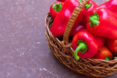 Kahverengi bir arka plan üzerinde hasır sepet kırmızı (tatlı) biber. Kopyalama alanı.