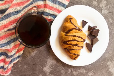 Gri bir arka plan üzerinde kahve ve çikolata kruvasan fincan. Üst te. Kahvaltı konsepti.