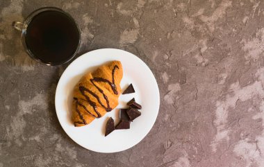  Gri bir arka plan üzerinde kahve ve çikolata kruvasan fincan. Yukarıdan bak. Kopyalama alanı.