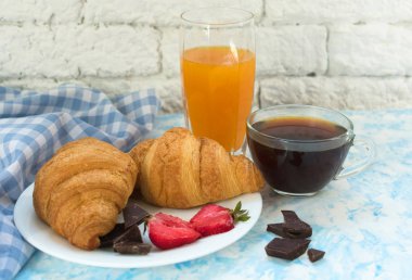 İki çikolatalı kruvasan çilek, bir fincan kahve ve bir bardak portakal suyu. Close. Kahvaltı konsepti.