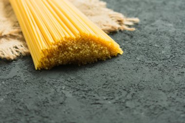 Doğal kumaş bir arka plan üzerinde Ham uzun spagetti. Sarı İtalyan makarnası. Ham spagetti bolonez. Spagetti için ambalaj kavramı. Close.