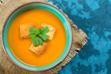 Çorba kabak püresi ve mavi bir arka plan üzerinde küçük kruton. Üst te. Sonbahar menü konsepti. Kopyalama alanı.