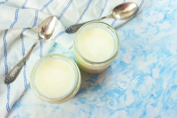 Griekse Yoghurt Glazen Potten Met Lepels Een Blauwe Achtergrond Bovenaanzicht — Stockfoto