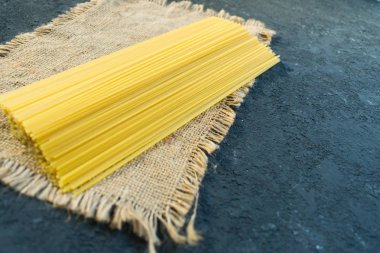  Siyah arka planda çiğ, uzun bir spagetti. Sarı İtalyan makarnası. Çiğ spagetti bolonez. Spagetti paketleme kavramı. Boşluğu kopyala.