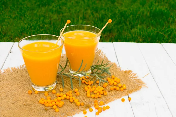 Beyaz arka planda iki bardak sağlıklı deniz dikenli meyve suyu..