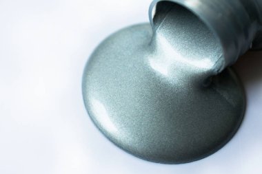  Beyaz arka plandaki bir şişeden gümüş boya döküldü. Boşluğu kopyala.