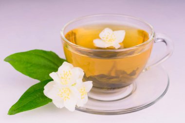 Bir fincan yasemin çayı ve yasemin çiçekleri beyaz arka planda. Yakın plan.