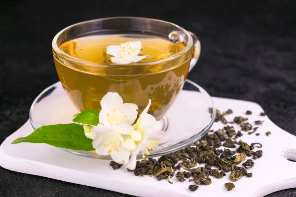 A cup of jasmine tea and jasmine flowers on a black background.Close-up.