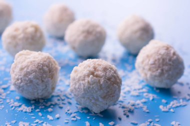 Hindistan cevizi ve beyaz çikolata topları mavi arka planda top şeklinde..