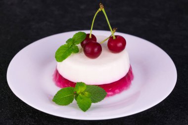Siyah arka planda vişneli jöleli Panacotta tatlısı..