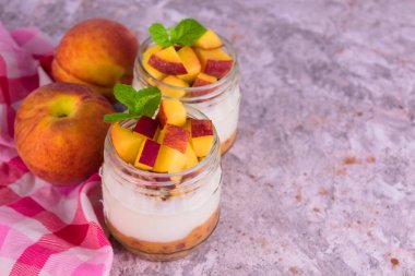 Gri arka planda şeftalili iki porsiyon yoğurt. Boşluğu kopyala.