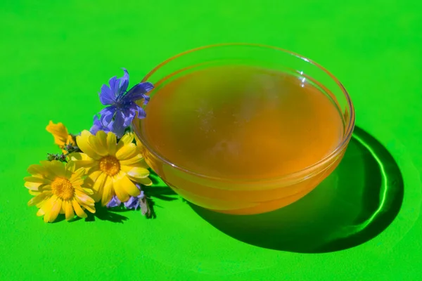 Taze çiçek bal cam bir kase içinde parlak yeşil bir zemin üzerinde.