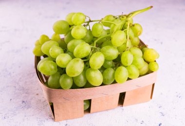 Beyaz arka planda bir sepetin içindeki üzümler.