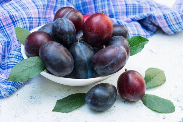 Beyaz bir masada sulu ve olgun bir erik tabağı. Yakın plan..