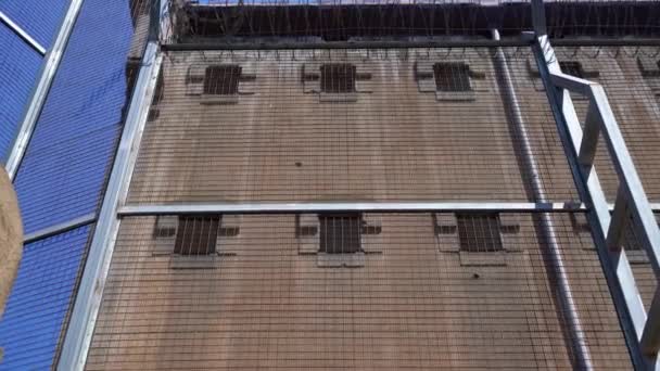Parede da prisão com janelas pequenas com barras e uma cerca alta com arame farpado — Vídeo de Stock