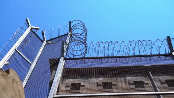 Cerca alta de la prisión con alambre de púas contra un cielo despejado. vista inferior — Vídeos de Stock