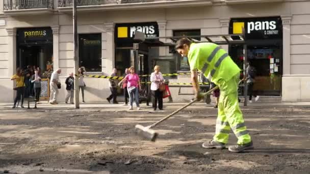 Trabalhadores rodoviários que reparam uma estrada contra uma paragem de autocarro queimada — Vídeo de Stock
