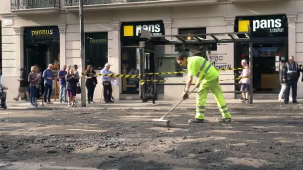 Дорожный рабочий подметает асфальт во время ремонта тротуара — стоковое видео