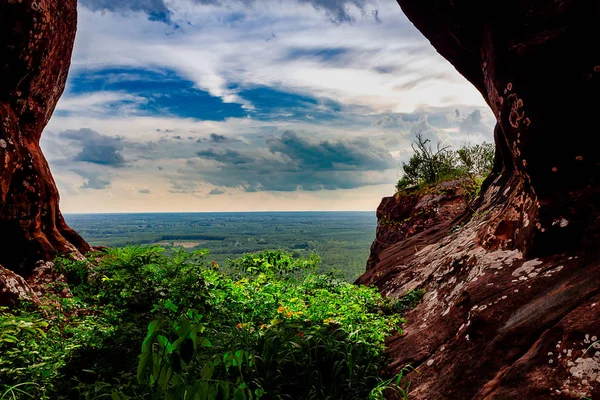 Uitkijkend vanaf een berg vanuit een vegetatie gevulde grot — Stockfoto