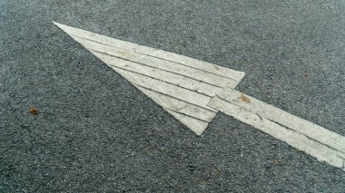 Gri asfalt bir yolda, arabanın gitmesi gereken yönü gösteren beyaz bir ok..