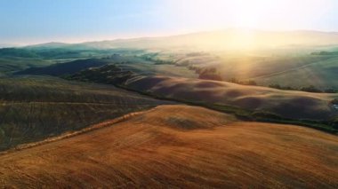 Hareketli hava atış hasat alanları, ağaçlar ve tepeler. Batan güneşin güzel renklerle manzaralı.