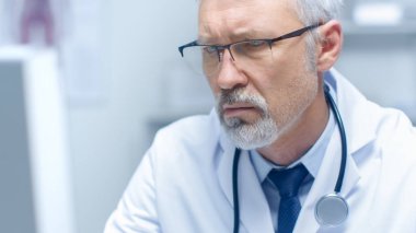 Kişisel bilgisayarınızda çalışan beyaz saçlı Doktor yakın çekim portre. Ofisinin parlak olduğunu ve ışık.