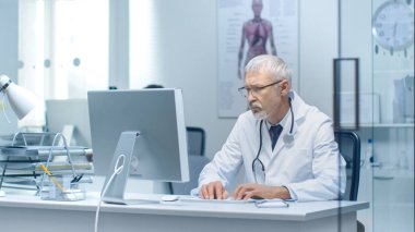 Kıdemli doktor ve parlak ve ışık ofiste Pc üzerinde çalışan asistanı.