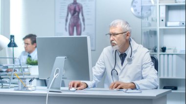 Kıdemli doktor ve parlak ve ışık ofiste Pc üzerinde çalışan asistanı.