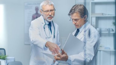 İki uzman doktor hastanın günlük tartışıyor. Her ikisi are kıdemli ve deneyimli. Onların ofis Modern ve saygıdeğer görünüyor.