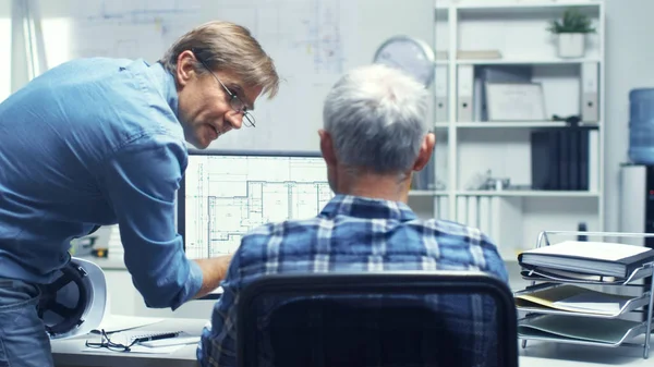 Two Senior Architectural Engineers Working With Building Plan on a Personal Computer. They Actively Discuss Various Plans and Schemes.