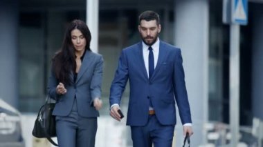 İş kadını ve özel takım elbiseli bir adam iş meşgul büyük şehir sokakta yürümek.