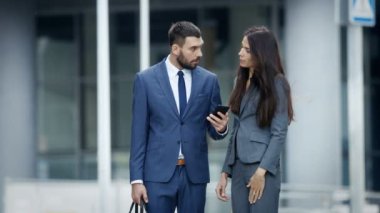 İş kadını ve iş adamı kullanma Smartphone ve konuşmak sokaklarda meşgul büyük şehir. İkimiz de zarif şık gibi.