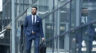 İş adamı bir çanta ile gülümseyen merdivenlerden aşağı gider ve onun Smartphone denetler, o iş bölgesinde mutludur.