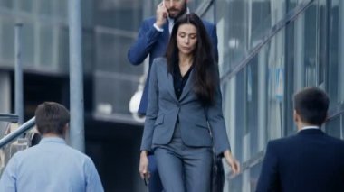 Erkek ve kadın iş adamları büyük şehir iş bölgesi sokak üzerinde yürüme. Her iki şık gri giyer / mavi uyarlanmış takım elbise, Erkek tutan bir çanta. Yatırımcılar toplantı için acele etseler.