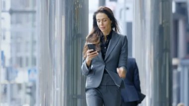 İş kadını Smartphone Merkez iş bölgesi Street yürüyüş sırasında kullanır. Her şekilde, büyük iş yapmak emin kadın.