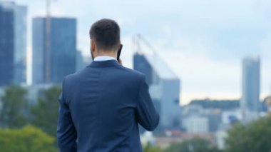 Telefonda konuşurken kendinden emin iş adamı orta vurdu. Sırtı ile gökdelenler ve Park görünür ile büyük şehre durduğunu.
